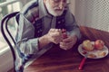 Senior with grey hair and beard sitting alone in the kitchen eating breakfast Royalty Free Stock Photo