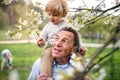 Senior grandfather with toddler grandson standing in nature in spring.