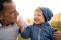 Senior grandfather with toddler grandson standing in nature in spring.