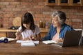 Senior grandmother helping schoolkid granddaughter to do homework Royalty Free Stock Photo