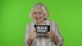 Senior grandmother showing Black Friday inscription note, smiling, looking satisfied with low prices