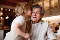 Senior grandmother with small toddler boy making cakes at home, kissing.