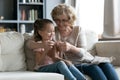 Senior grandmother teaches little granddaughter to knit