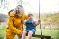 Senior grandmother with toddler granddaughter on a swing in garden in spring. Royalty Free Stock Photo