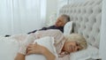 Senior grandparents couple lying and sleeping in bed. Woman getting disturbed with man snoring Royalty Free Stock Photo