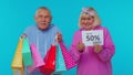 Senior grandparents showing shopping bags and Up To 50 Percent Off banner text, Black Friday holiday