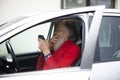 Senior with a gray beard is sitting in the car and holding a photo camera Royalty Free Stock Photo