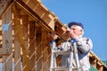 Senior gray-haired builder collects the frame of a wooden country house