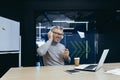 Senior gray haired businessman boss working inside modern office using laptop at work, mature man in headphones Royalty Free Stock Photo