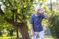 Senior gray-haired man doing sports and jogging in the park, standing and wiping sweat from his forehead, resting tired Royalty Free Stock Photo