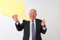 Senior grey-haired businessman holding speech bubble over isolated white background happy with big smile doing ok sign, thumb up Royalty Free Stock Photo