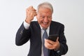 Senior grey-haired businessman using smartphone standing over isolated white background annoyed and frustrated shouting with Royalty Free Stock Photo