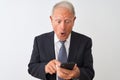 Senior grey-haired businessman using smartphone standing over isolated white background scared in shock with a surprise face, Royalty Free Stock Photo