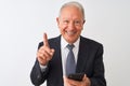 Senior grey-haired businessman using smartphone standing over isolated white background surprised with an idea or question Royalty Free Stock Photo