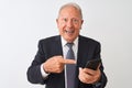 Senior grey-haired businessman using smartphone standing over isolated white background very happy pointing with hand and finger Royalty Free Stock Photo