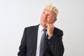 Senior grey-haired businessman wearing crown king over isolated white background with hand on chin thinking about question, Royalty Free Stock Photo