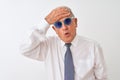 Senior grey-haired businessman wearing tie and sunglasses over isolated white background stressed with hand on head, shocked with Royalty Free Stock Photo