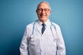 Senior grey haired doctor man wearing stethoscope and medical coat over blue background with a happy and cool smile on face Royalty Free Stock Photo