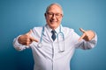 Senior grey haired doctor man wearing stethoscope and medical coat over blue background looking confident with smile on face, Royalty Free Stock Photo