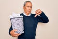 Senior grey-haired man holding full paper bin with crumpled papers over white background with angry face, negative sign showing Royalty Free Stock Photo