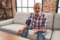 Senior grey-haired man measuring pulse using tensiometer at home