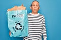 Senior grey-haired man recycling holding bag with cardboard to recycle over blue background with a confident expression on smart Royalty Free Stock Photo