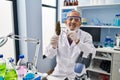 Senior grey-haired man scientist holding cannabis herb with tweezers at laboratory