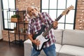 Senior grey-haired man singing song playing electrical guitar at home Royalty Free Stock Photo