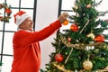 Senior grey-haired man smiling happy decorating christmas tree at home
