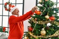 Senior grey-haired man smiling happy decorating christmas tree at home