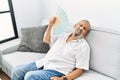 Senior grey-haired man using handfan at home Royalty Free Stock Photo