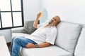 Senior grey-haired man using handfan at home Royalty Free Stock Photo