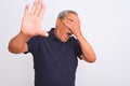 Senior grey-haired man wearing black casual polo standing over isolated white background covering eyes with hands and doing stop Royalty Free Stock Photo