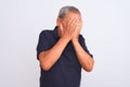 Senior grey-haired man wearing black casual polo standing over isolated white background with sad expression covering face with Royalty Free Stock Photo