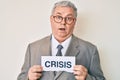 Senior grey-haired man wearing business suit holding crisis paper clueless and confused expression Royalty Free Stock Photo