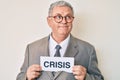 Senior grey-haired man wearing business suit holding crisis paper smiling looking to the side and staring away thinking Royalty Free Stock Photo