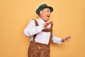 Senior grey-haired man wearing german traditional octoberfest suit over yellow background Dancing happy and cheerful, smiling Royalty Free Stock Photo