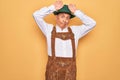 Senior grey-haired man wearing german traditional octoberfest suit over yellow background Doing bunny ears gesture with hands Royalty Free Stock Photo