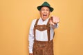 Senior grey-haired man wearing german traditional octoberfest suit over yellow background pointing displeased and frustrated to Royalty Free Stock Photo