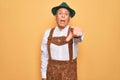 Senior grey-haired man wearing german traditional octoberfest suit over yellow background pointing displeased and frustrated to Royalty Free Stock Photo