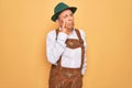 Senior grey-haired man wearing german traditional octoberfest suit over yellow background Pointing to the eye watching you Royalty Free Stock Photo