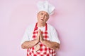 Senior grey-haired man wearing professional baker apron begging and praying with hands together with hope expression on face very Royalty Free Stock Photo