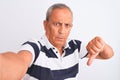 Senior grey-haired man wearing striped polo make selfie over isolated white background with angry face, negative sign showing Royalty Free Stock Photo