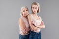 Senior grey-haired mother leaning on her daughter back