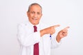 Senior grey-haired scientist man wearing coat standing over isolated white background smiling and looking at the camera pointing Royalty Free Stock Photo