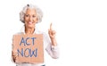 Senior grey-haired woman holding act now banner surprised with an idea or question pointing finger with happy face, number one
