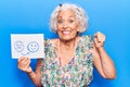 Senior grey-haired woman holding sad to happy emotion paper screaming proud, celebrating victory and success very excited with Royalty Free Stock Photo