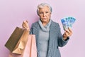 Senior grey-haired woman holding shopping bags and south africa rands banknotes depressed and worry for distress, crying angry and