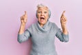 Senior grey-haired woman pointing up with fingers celebrating crazy and amazed for success with open eyes screaming excited Royalty Free Stock Photo