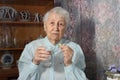 Senior grey-haired woman taking pills, holding a glass of water Royalty Free Stock Photo